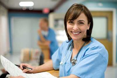 female nurse smiles while holding medical records