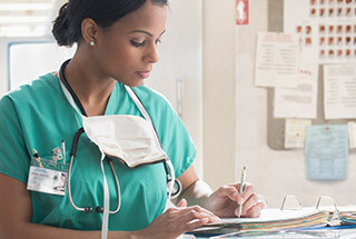 Female nurse writing in a binder